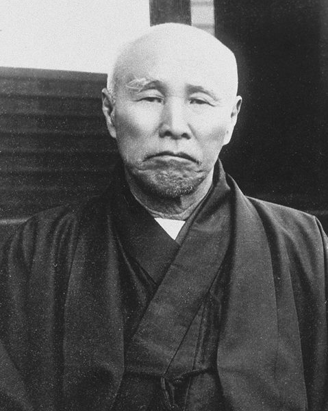 着物と羽織を着た、頭をそった年配の男性
