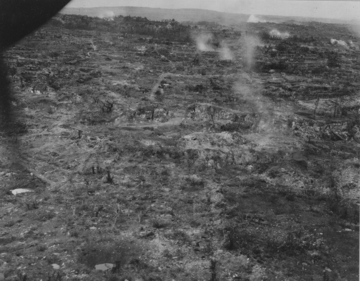 空から写した、木も家もなくなり、土がむき出しになった丘。ところどころから煙が上がっている白黒の写真