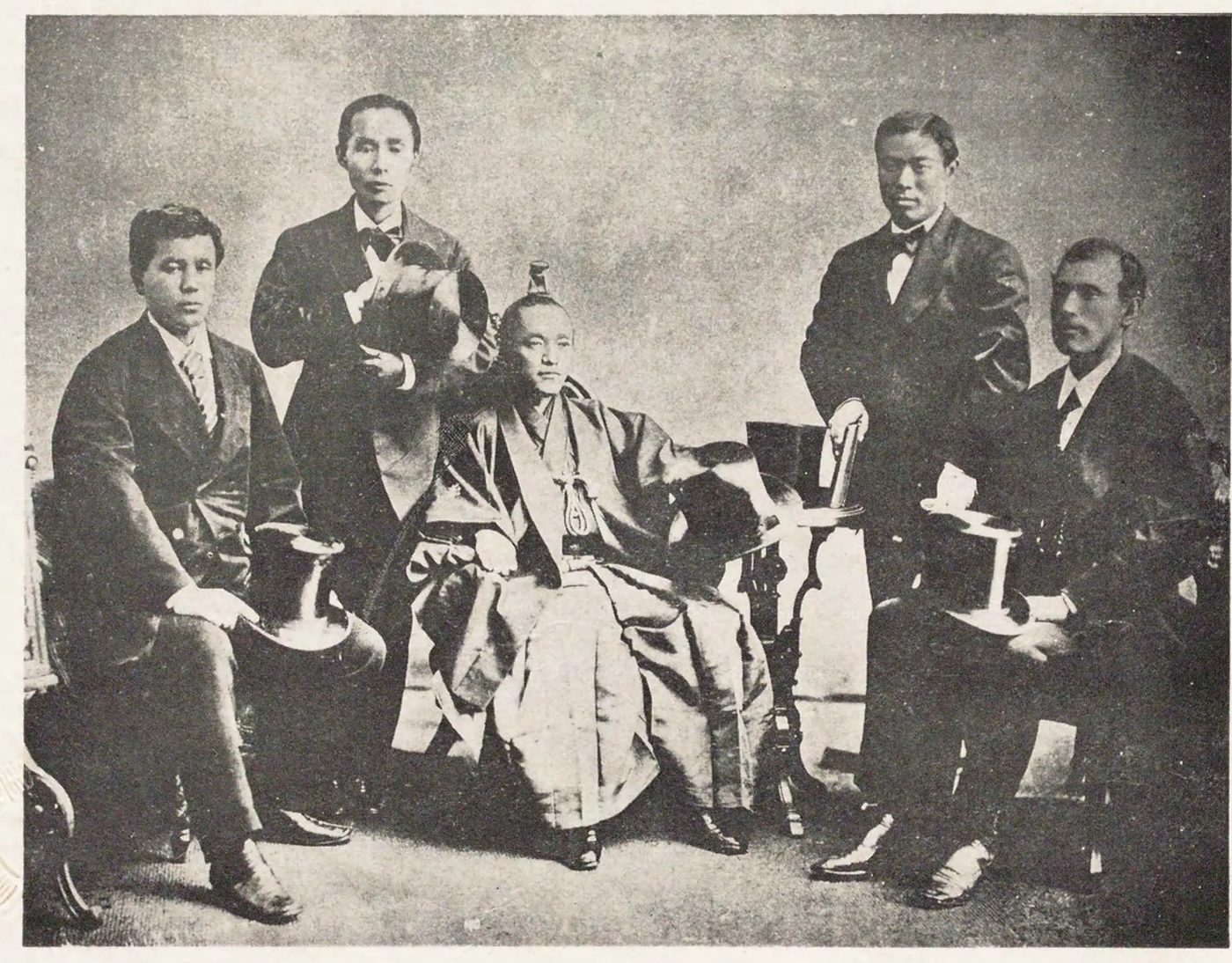 いすにすわった和服の男性を中心に、洋服の男性4人がならんだ古い写真