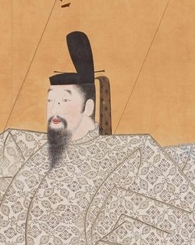 黒いぼうしをかぶり、白い着物と赤いはかまを着て、ひげのある男性がすわっている肖像画