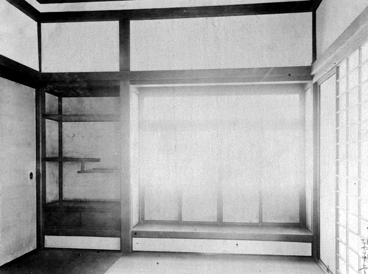 たたみの部屋の左に棚が組まれ、その右に窓の前の作りつけの机がある、白黒写真