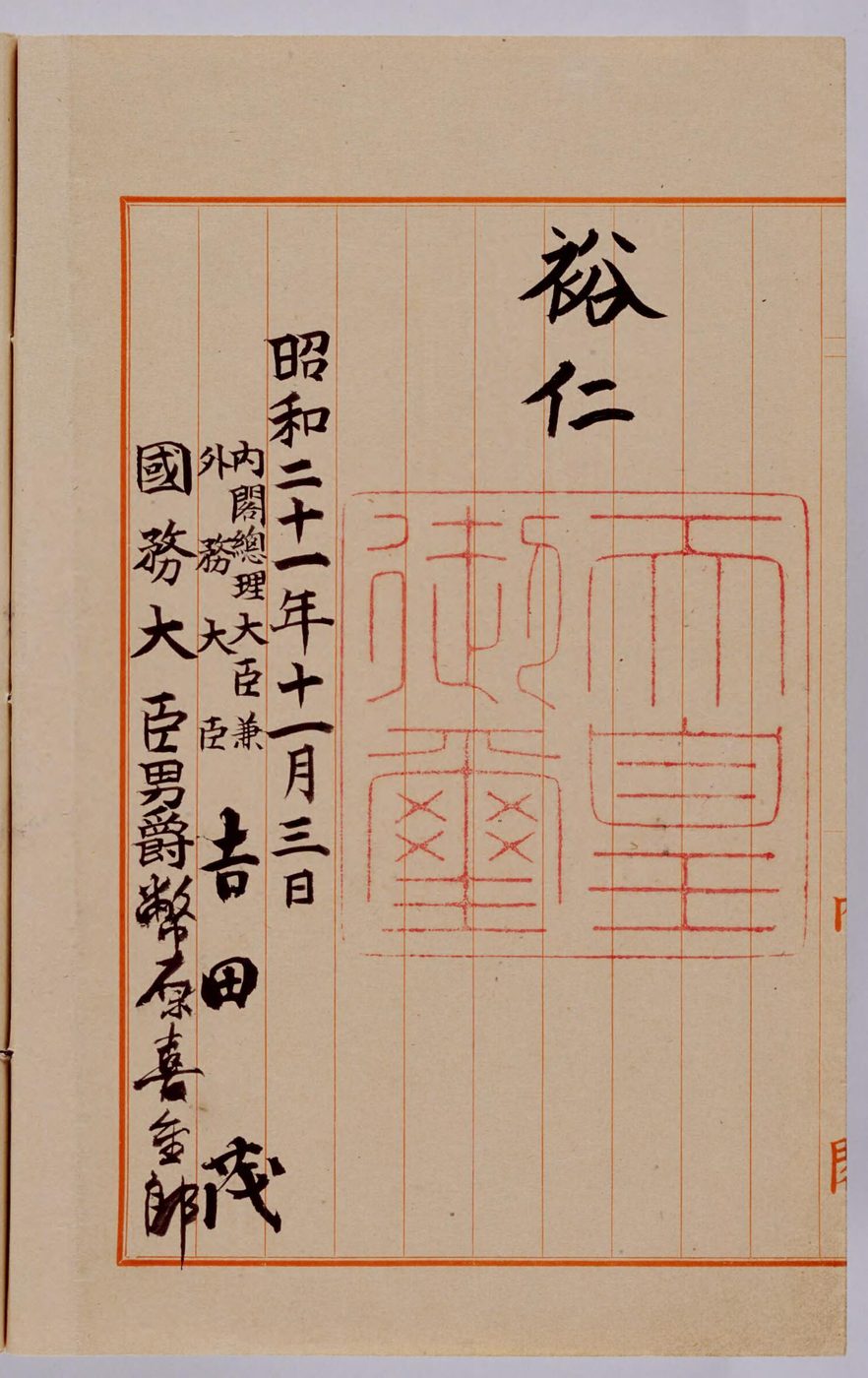 赤いけいの紙に、大きな赤い印がおされ、「昭和二十一年十一月三日」の日付と、吉田茂などの名前が筆で書かれた紙