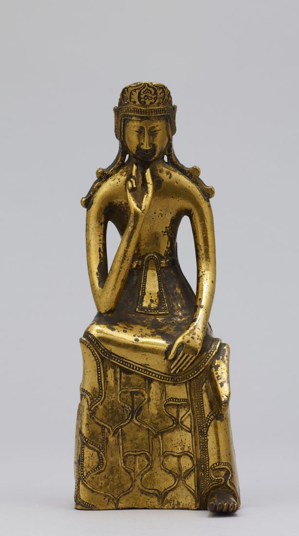 金色の小さな仏像。台にすわり、右足を左ひざにのせ、右手の指をほおに当てて考えこんでいる